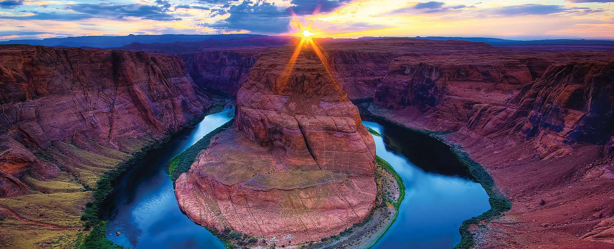 The sun sets over the Grand Canyon and Colorado River in Arizona during a national park vacation
