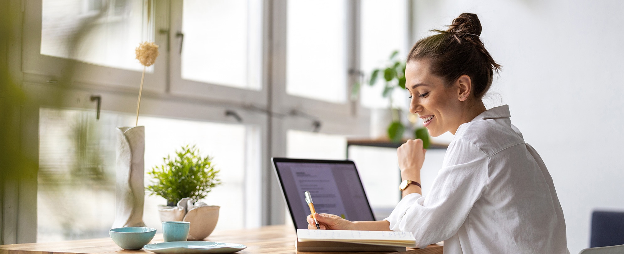 A woman sitting in front of her laptop and taking notes..