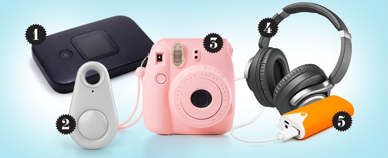 Five gift items on a light blue background: a black portable Wi-Fi box, gray luggage tracker, pink instant camera, black headphones, and an orange portable charger.