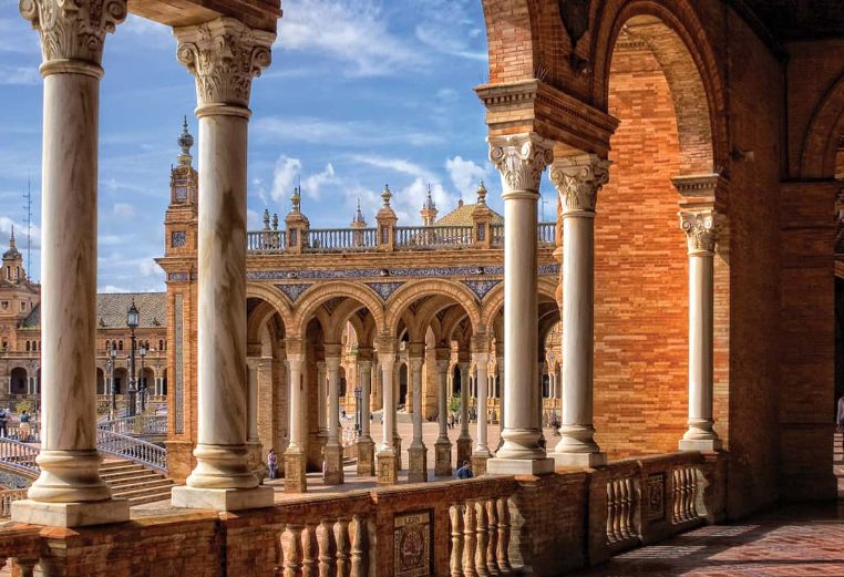 Marble columns, tall tower, and red stone architecture at the Plaza De Espana in Spain