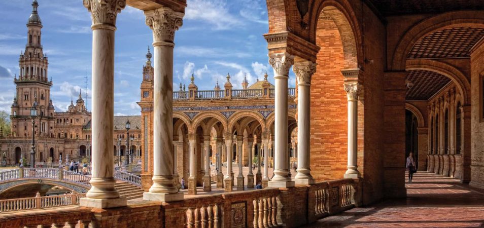 Marble columns, tall tower, and red stone architecture at the Plaza De Espana in Spain