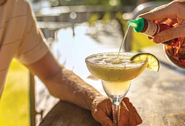 Bartender pouring liquor into a green frozen margarita at a Margaritaville Vacation Club resort bar.