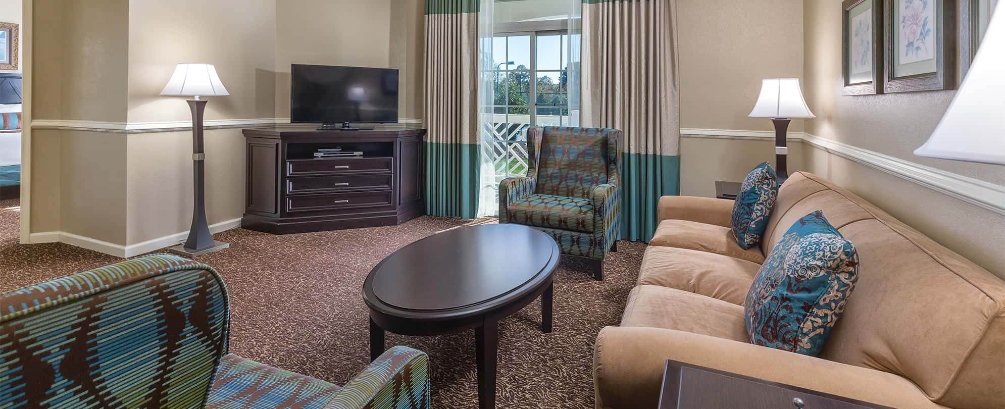 A living room furnished with couch, table, lamps and television in a Margaritaville Vacation Club suite. 