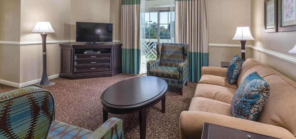 A living room furnished with couch, table, lamps and television in a Margaritaville Vacation Club suite. 