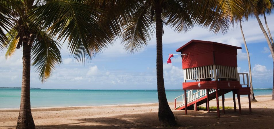 A red lifeguard shack and palm trees on Luquillo beach in San Juan, Puerto Rico.