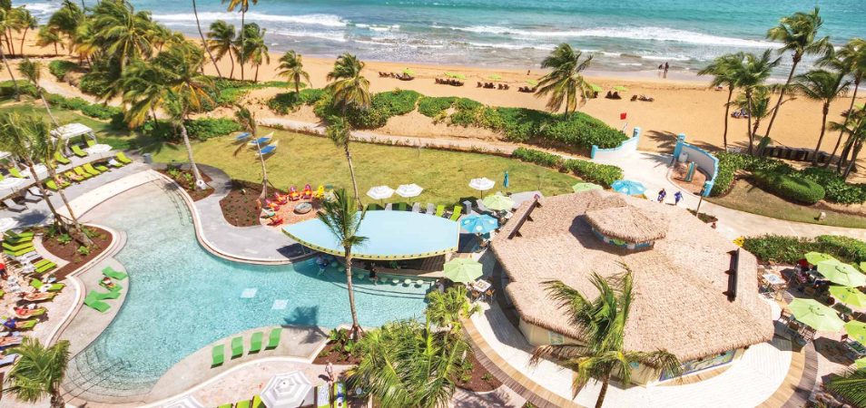 Birds-eye-view of the ocean and pool, with a boat-shaped swim-up bar, at Margaritaville Vacation Club by Wyndham - Rio Mar.
