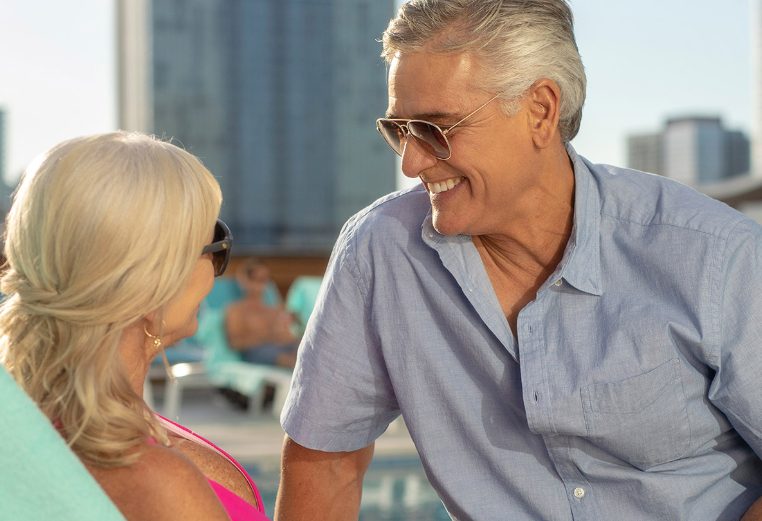 A smiling older man and woman sit by the rooftop pool at Margaritaville Vacation Club by Wyndham - Nashville.