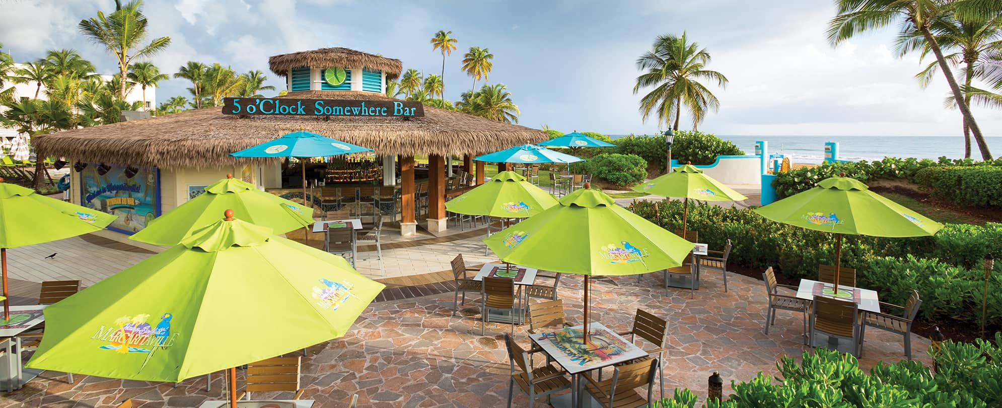 The "5 o'Clock Somewhere Bar" and tables with umbrellas at Margaritaville Vacation Club by Wyndham - Rio Mar in Puerto Rico.