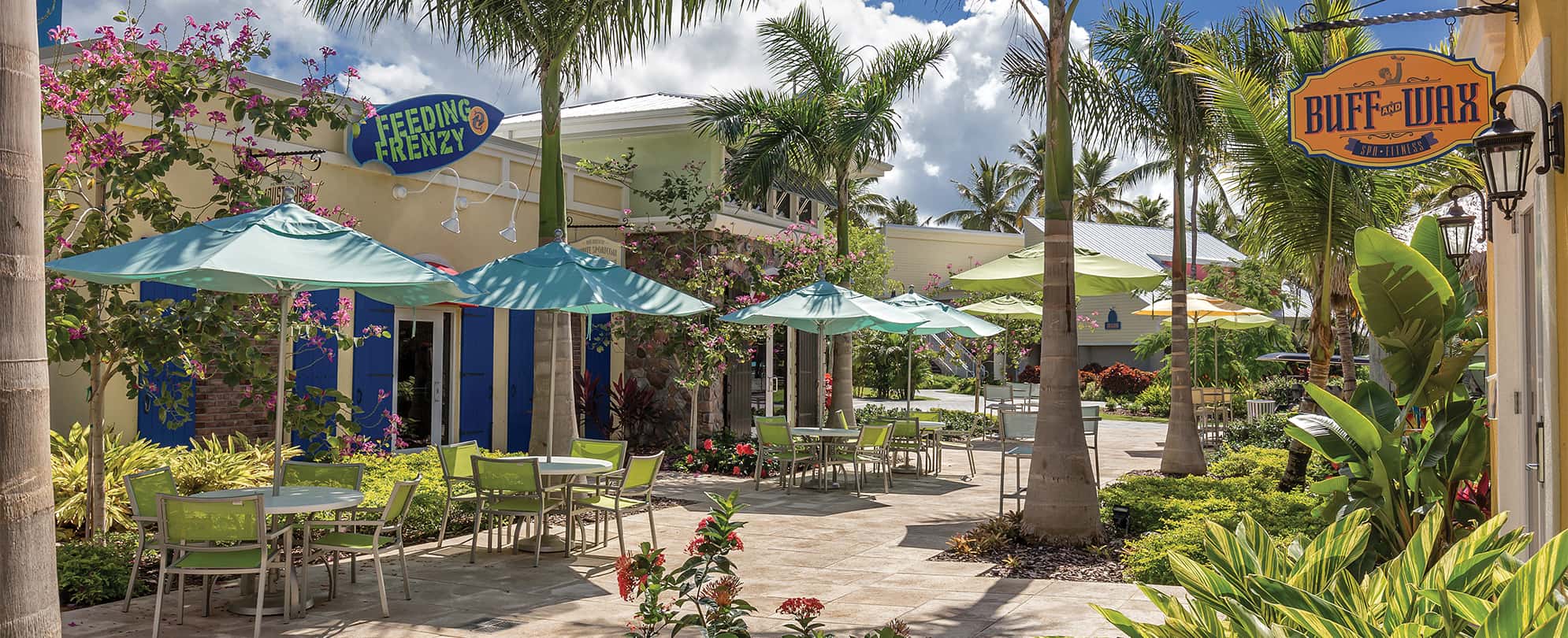 Tables with umbrellas outside a restaurant and the spa at Margaritaville Vacation Club by Wyndham - St. Thomas.