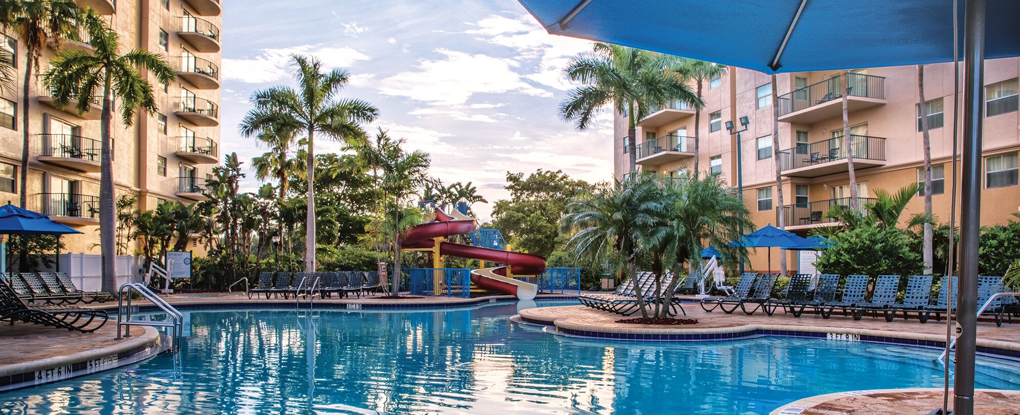 A pool surrounded by chairs and palm trees at WorldMark Palm-Air.