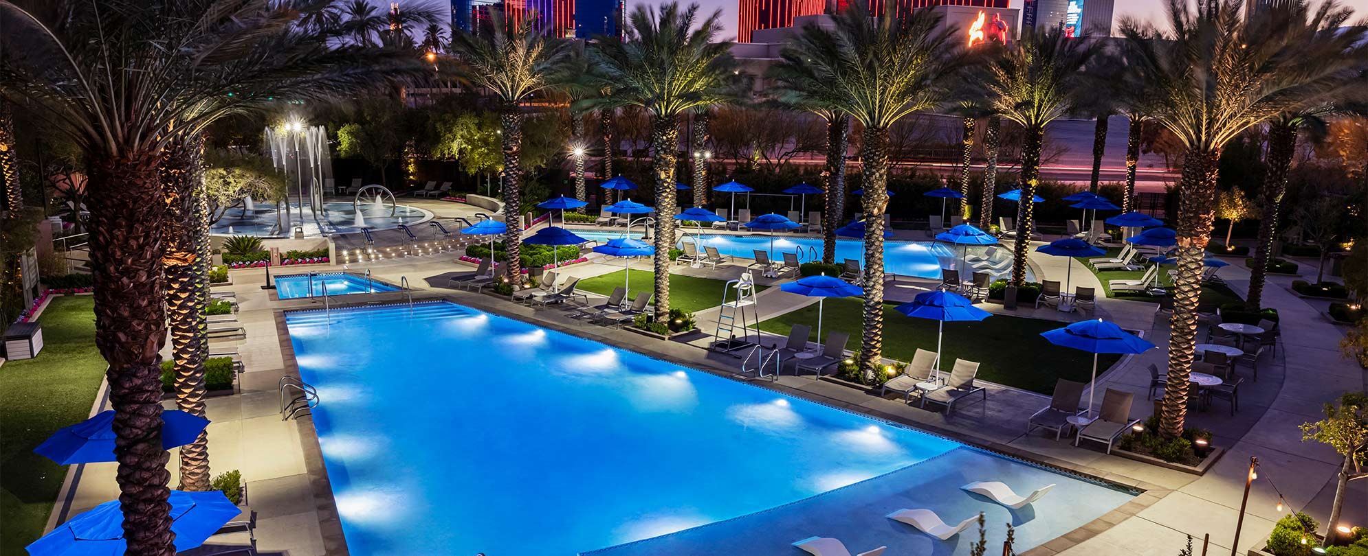 Pools lit up at night surrounded by palm trees at the Margaritaville Vacation Club by Wyndham - Desert Blue in Las Vegas, NV.