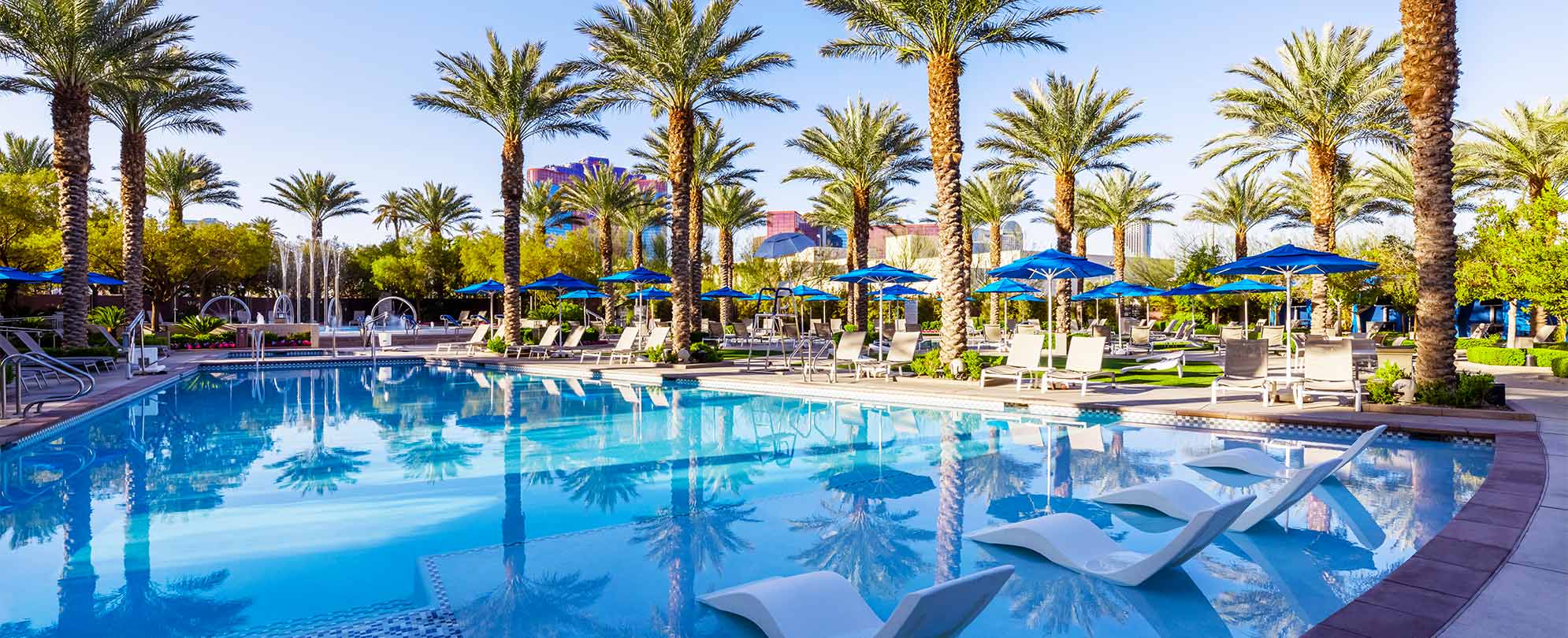 Lounge chairs and palm trees around the pool at Margaritaville Vacation Club by Wyndham - Desert Blue in Las Vegas, NV.